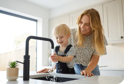 Family using water from a kitchen tap, representing smart water meter usage