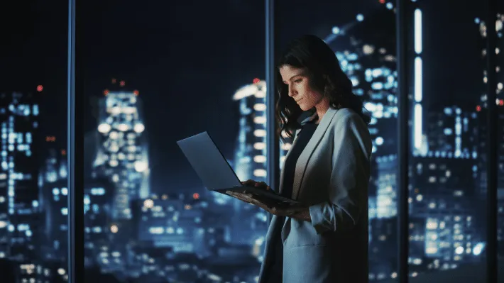 Woman viewing smart metering interface on a device with illuminated city buildings in the background